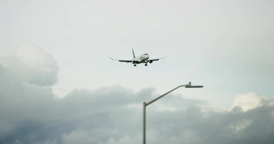 Aircraft flies closely over streetlights and leafless trees