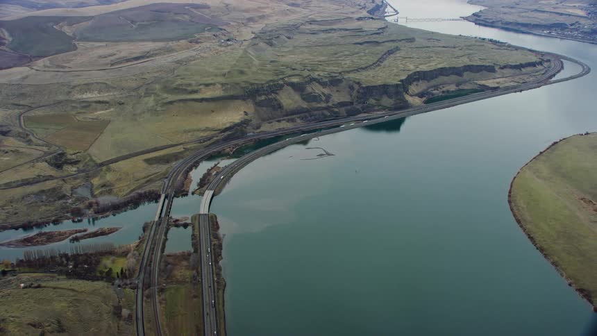 A large river bends through a landscape and is lined by a large road