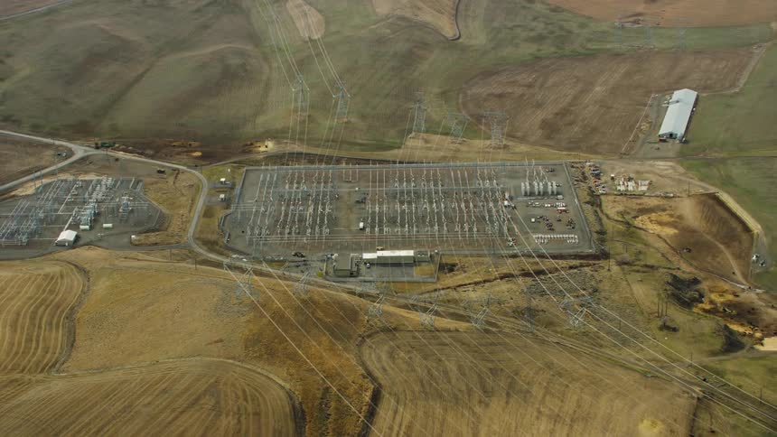 Aerial footage shows a large electrical utility facility with many power lines linking to it