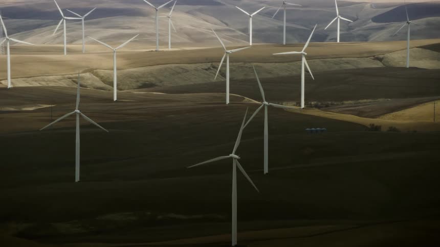 High altitude aerial shot of wind turbines creating clean renewable energy on a moody day in early Spring