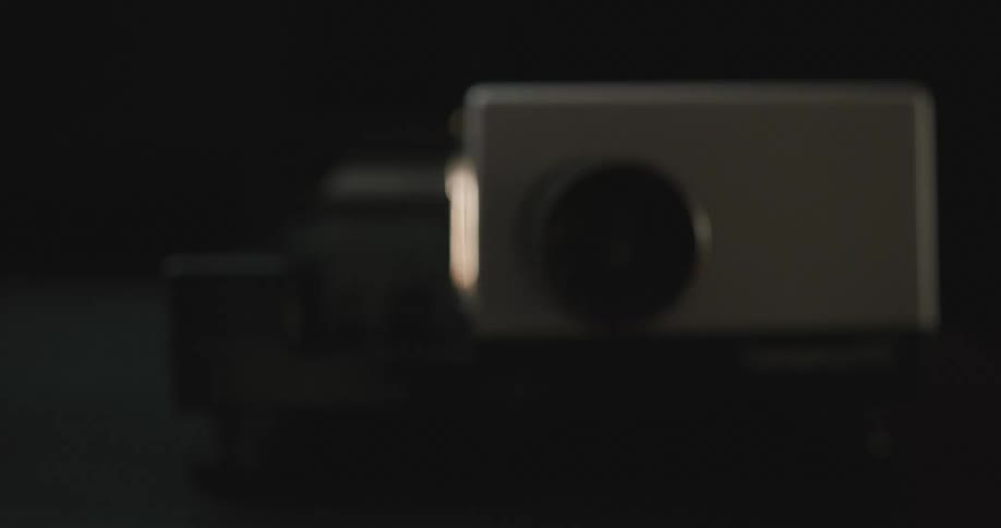 A white projector box displaying bright lights out the lens
