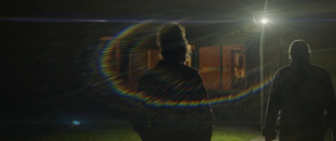 A man and woman walk up a driveway at night