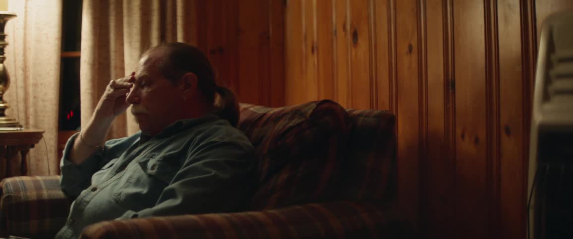 The man wipes his forehead in the chair