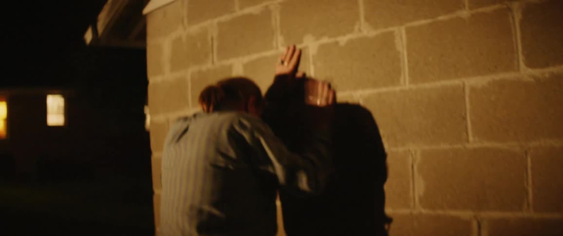 A man slams a stool against a garage then leans against the wall
