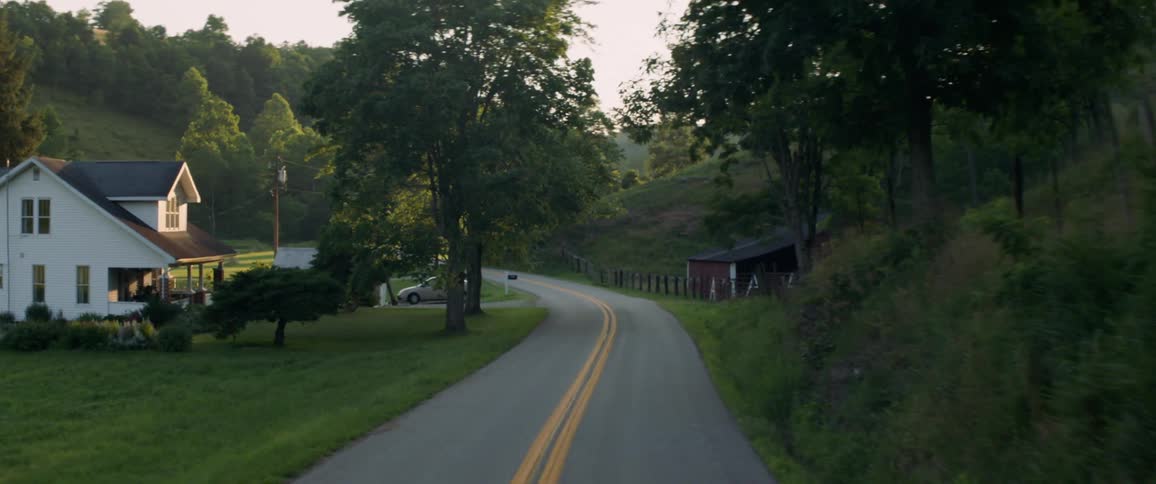 A vehicle travels on a country road at sunset