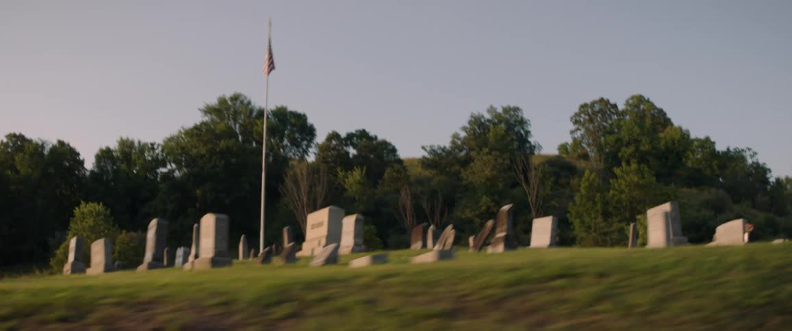 Passing by an american flag on a pole in a cemetery