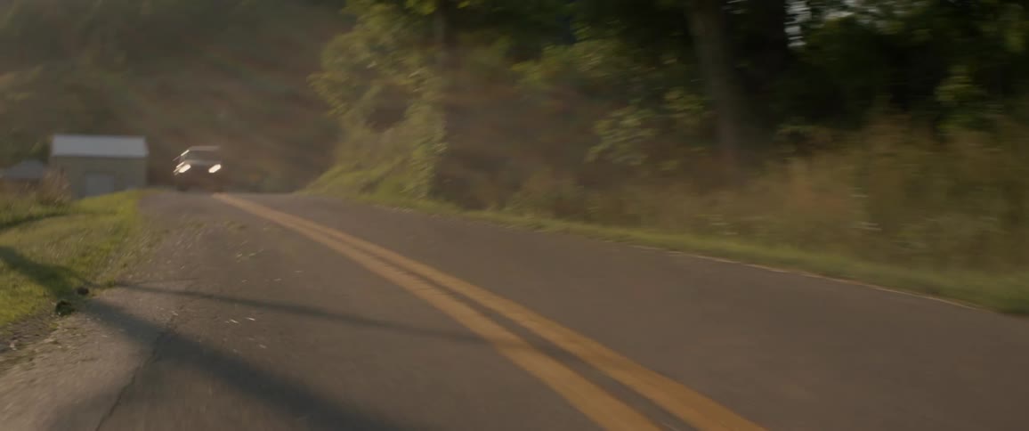 A truck travels on a rural road with a double yellow line on a sunny day
