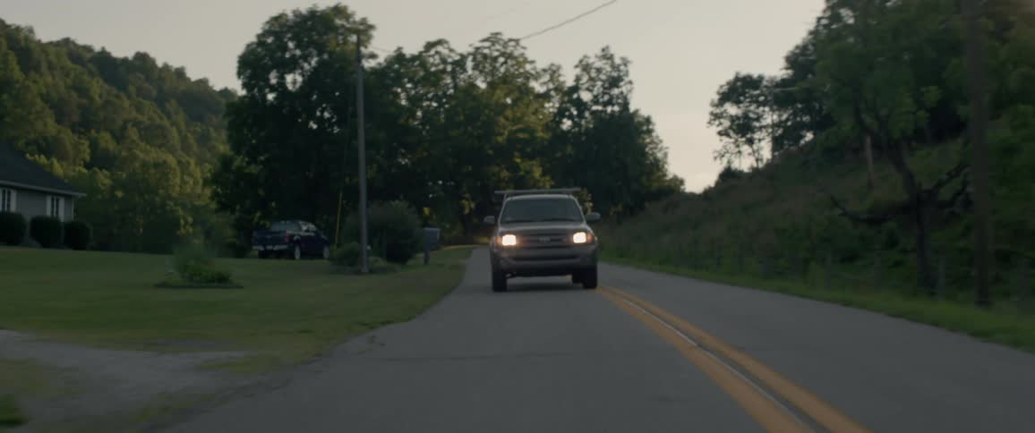 The vehicle travels down the road at sunset