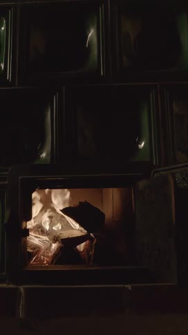 Placing a piece of wood into a wood stove