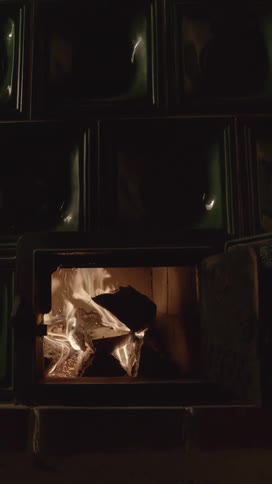 A furnace door being opened with fire logs and embers