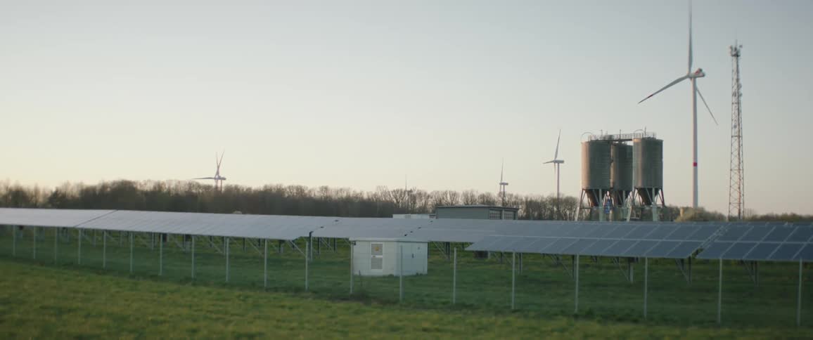 Wind turbines and solar panels sit on the field