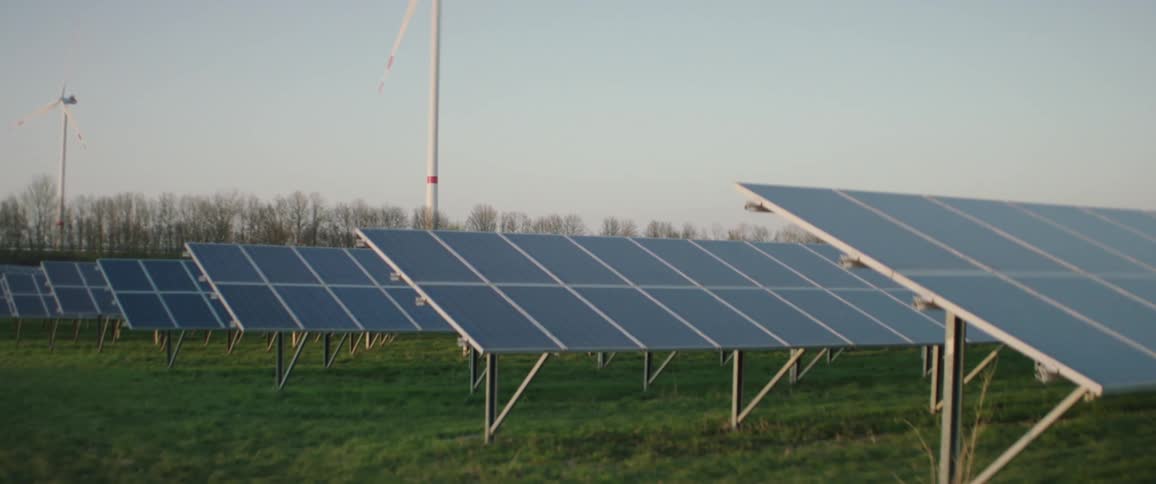 Wind turbines and solar panels at sunset