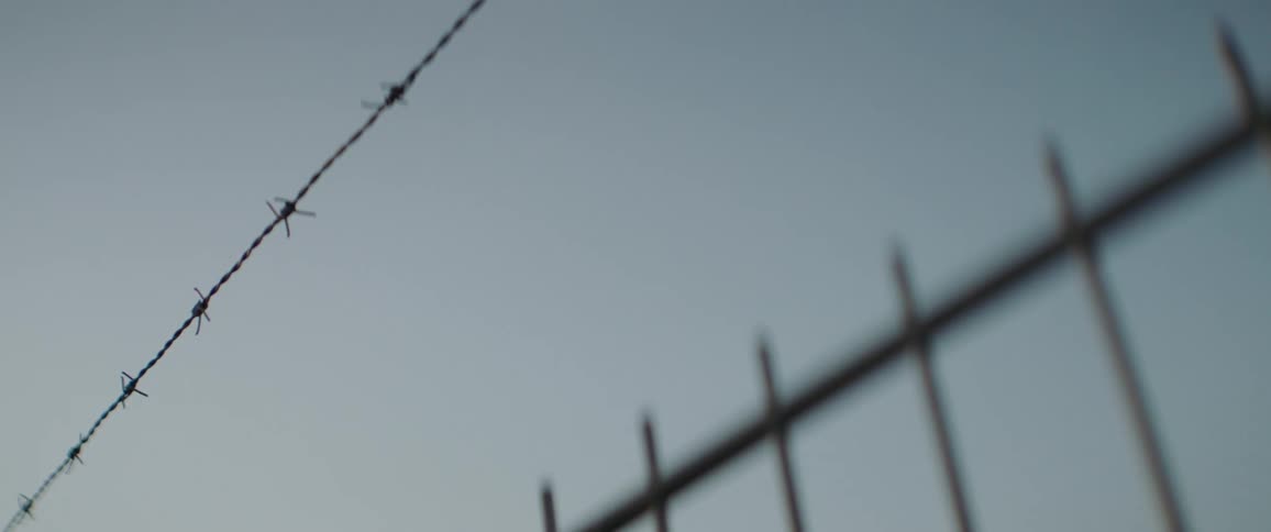 Fence with barbed wire against blue sky