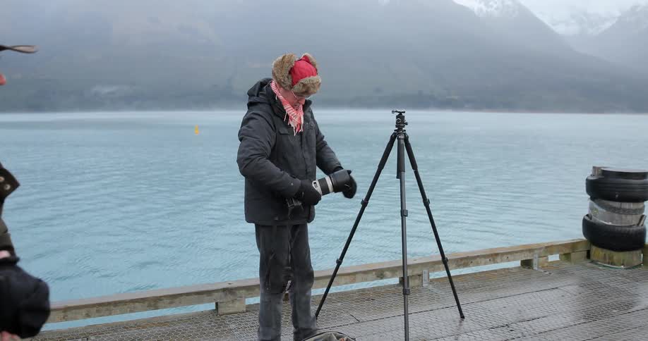 A man and woman are setting up cameras on a dock