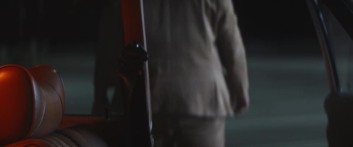 A man sitting in the drivers seat of an automobile opens the door and gets out of the car