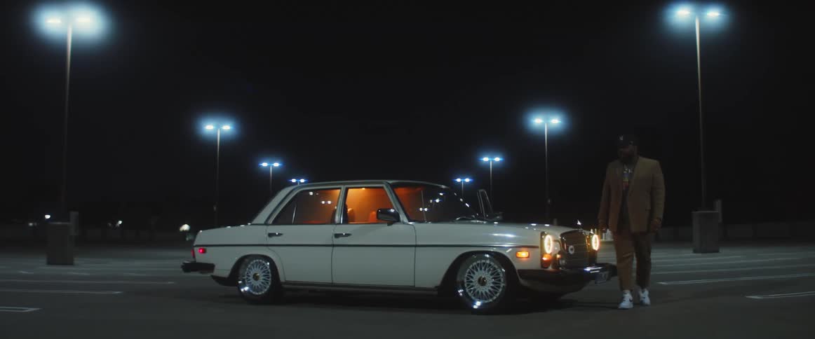 A man exits his automobile and slowly walks around its exterior