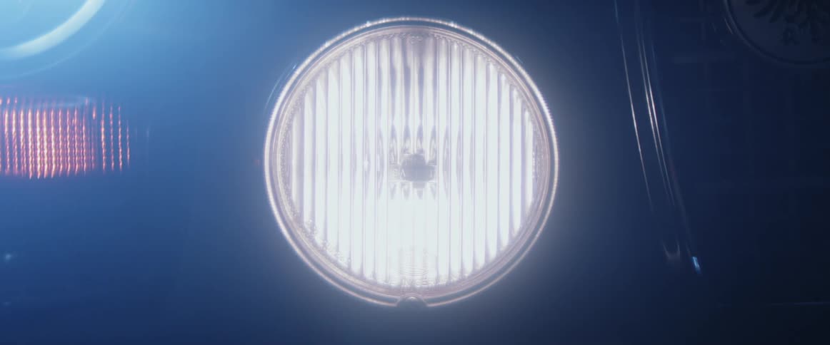 A car headlight turns on and off in the dark