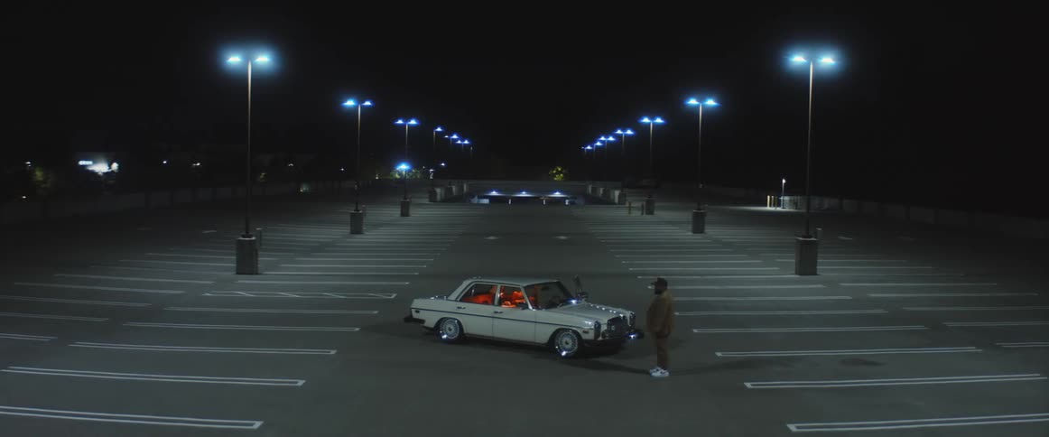 A man walks away from his car in an empty parking lot