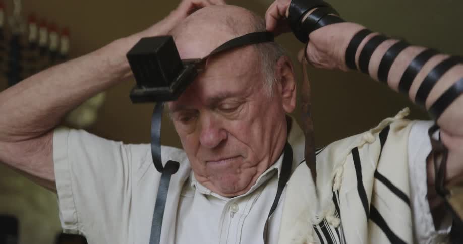 An elderly man putting on a head strap and straightening it on his forehead