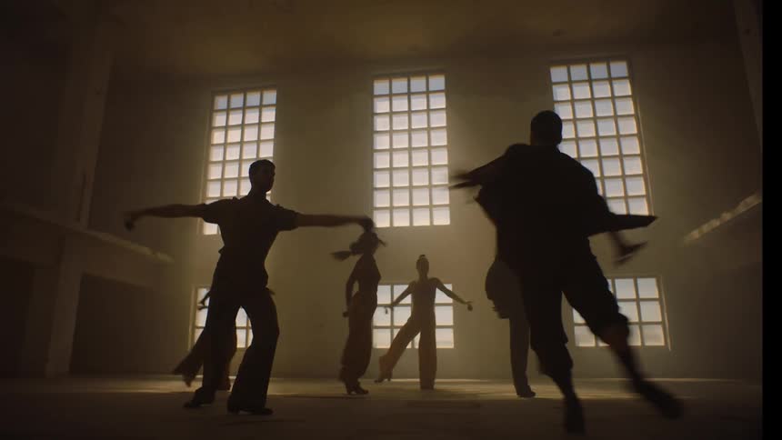 A group of people are dancing in an empty room