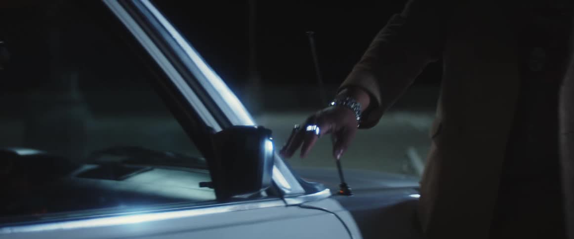 A man runs his hand across the side of a car caressing it