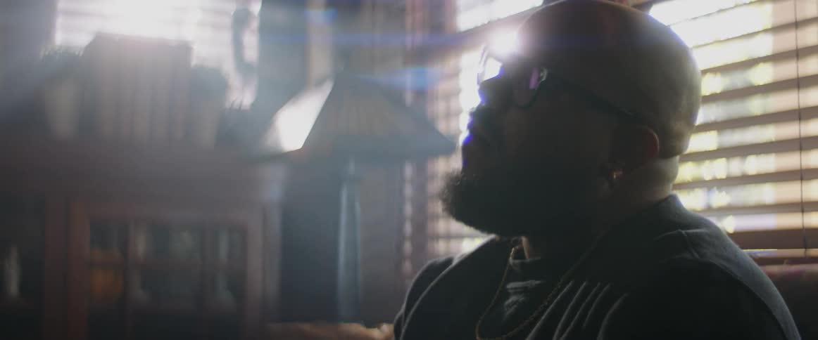 A man sitting on his couch looking around contemplatively and stressed
