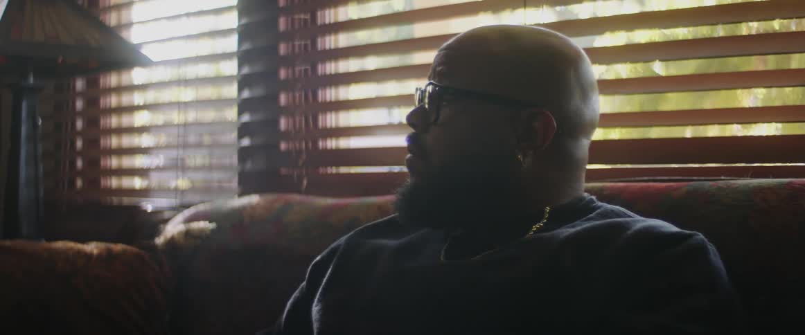 The man sits back on the couch