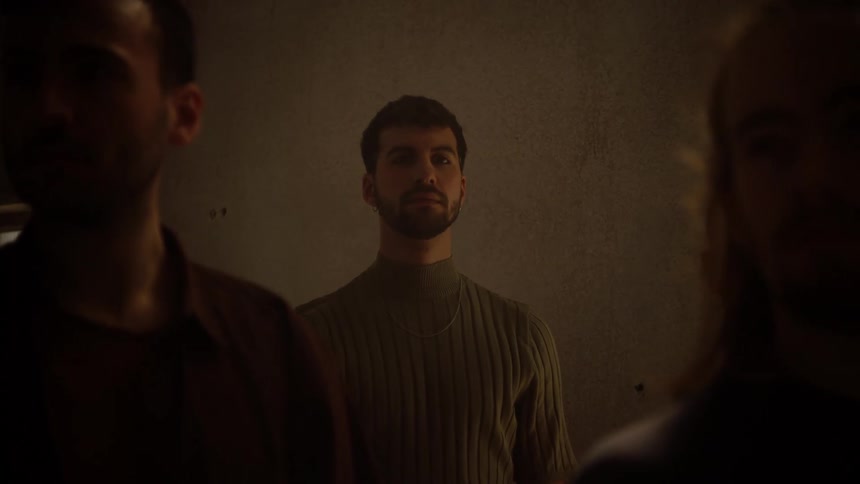 Group of interpretative dancers stand still inside a dimly lit room