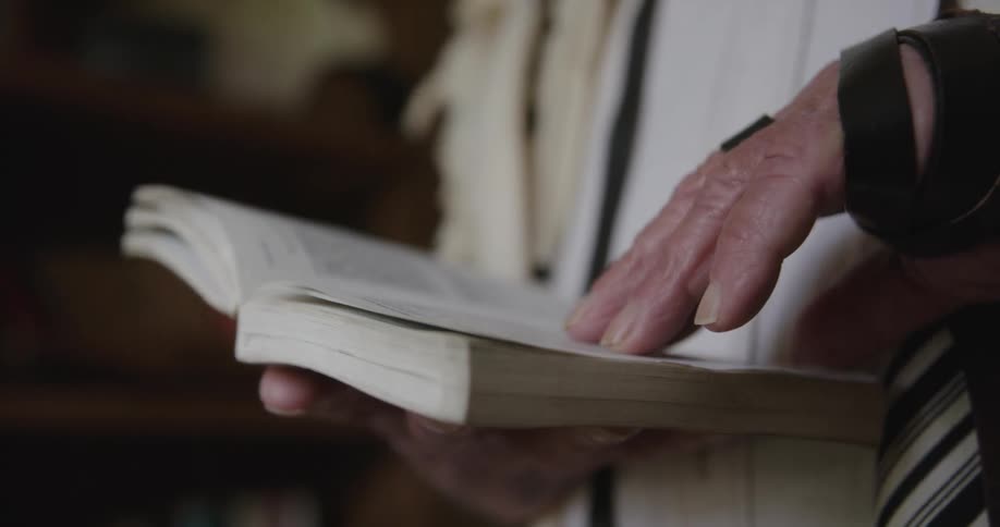 A man is reading a book and standing in a room