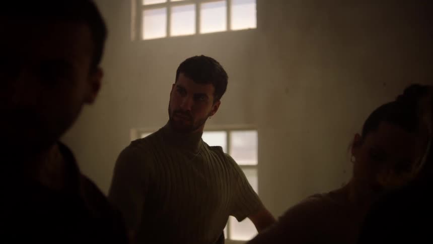 A man dances in a group of people inside a dimly lit warehouse
