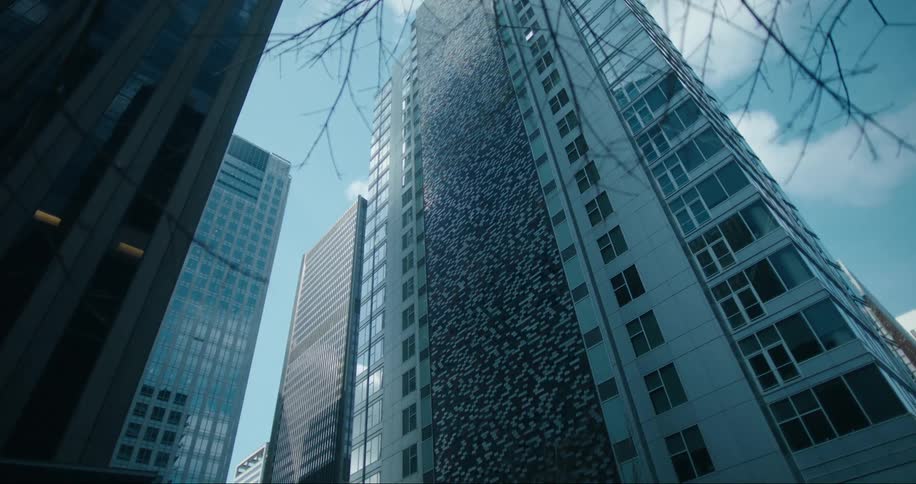 A tall sky scraper building in a city near other tall buildings in the daylight