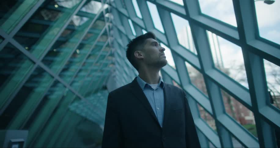 A portrait of a man standing near windows