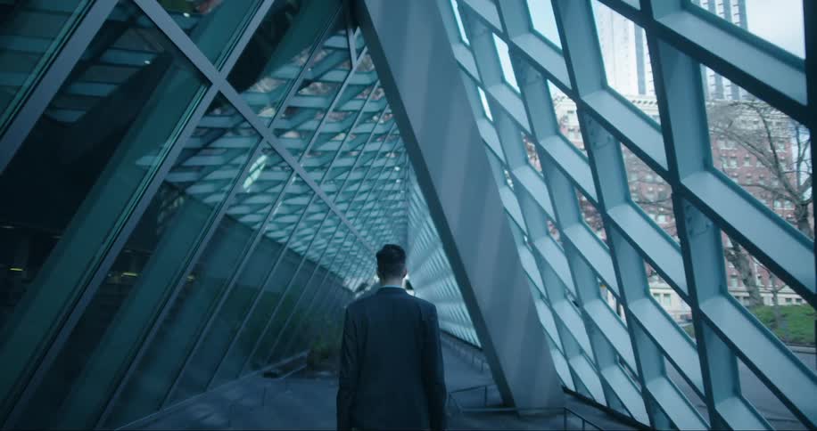 A man in a business suit walks through a corridor with interesting architecture