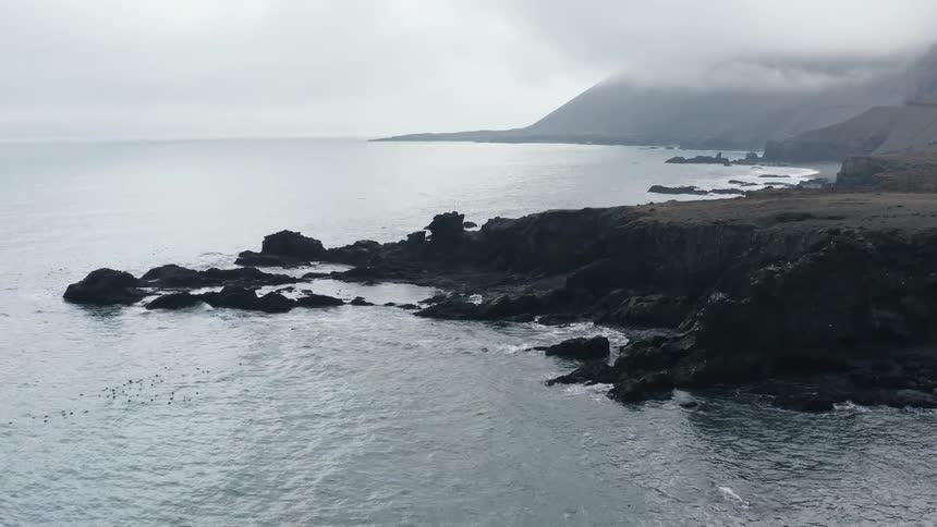 Aerial view of rock promontories on the coast next to the ocean at daytime