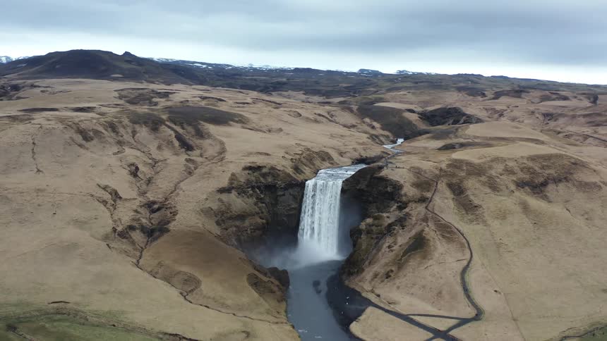 Aerial view of skogafoss river in iceland overcast and brown terrain