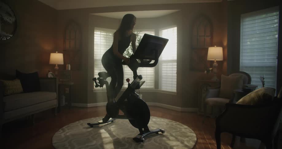 A woman is exercising on a machine in her house