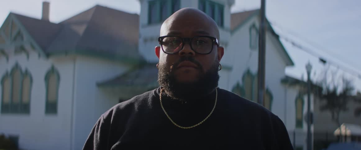 A black man on the street looking directly at the camera with a confident and modeling demeanor