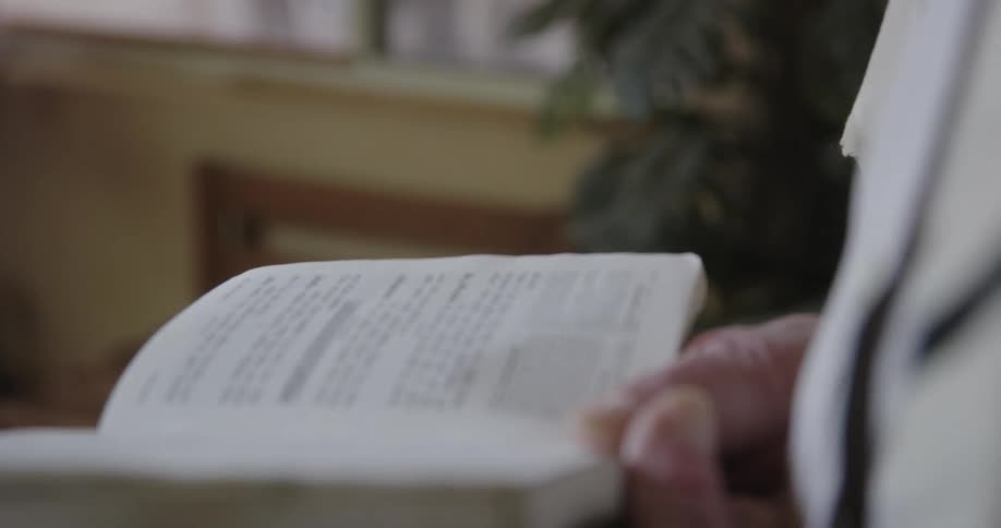 A man is standing indoors while holding an opened prayer book