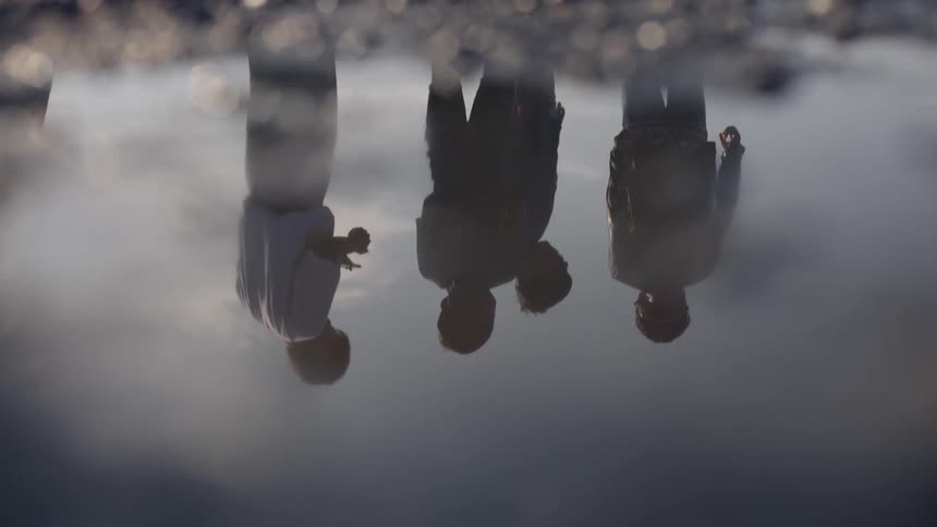 A puddle on the ground with the reflection of people walking in it