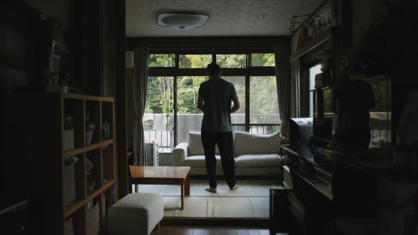 Man standing in front of the window in living room facing away from camera