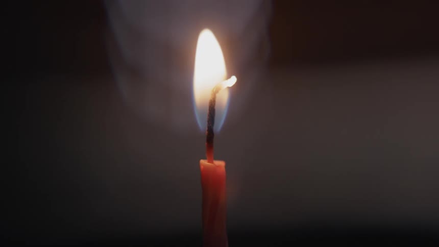A candle is lit with a lighter and the flame then proceeds to slowly burn the wick