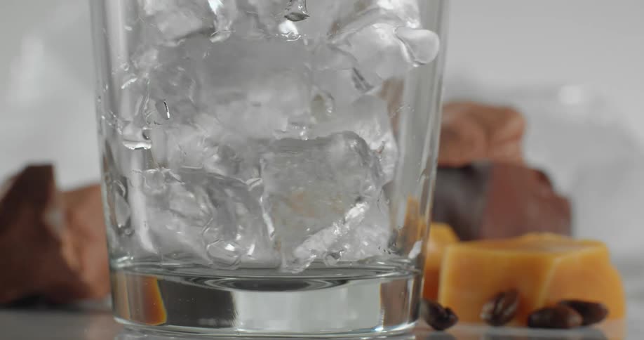 Ice fills glass sitting on surface near fudge blocks