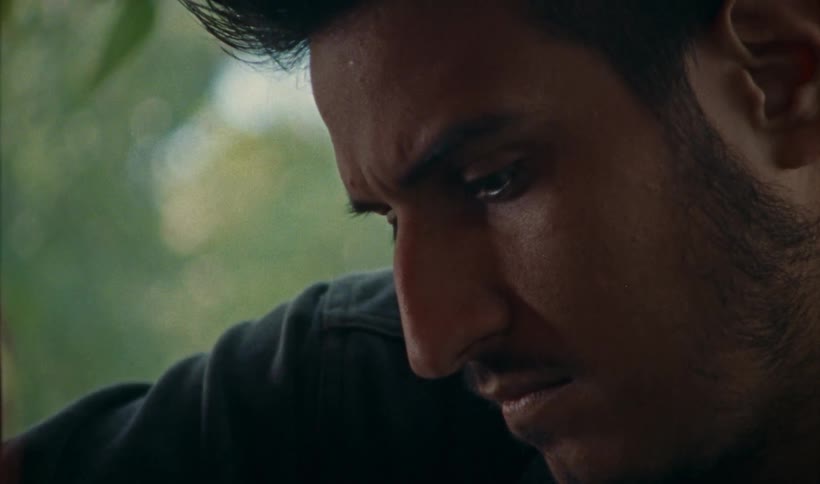 A close up of a mans face frowning while he works on equipment