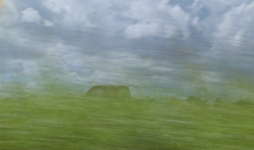 Red pickup truck drives on country road near the green fields