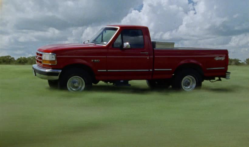A red truck is speeding through a field evoking a sense of motion and adventure