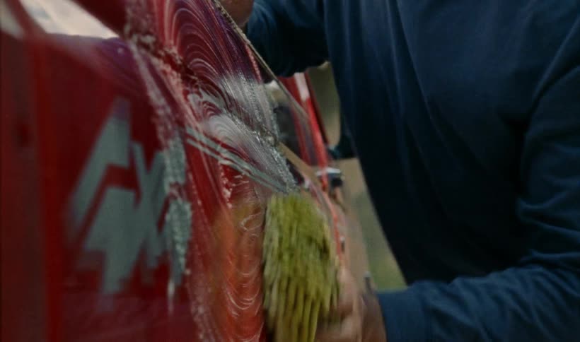 A man scrubs the exterior of a truck outdoors during the day