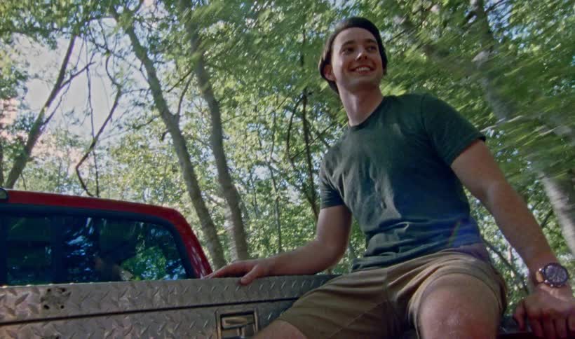 A young man smiling while riding in the back of a pickup truck