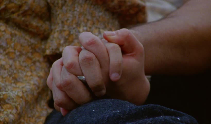 Two people holding hands tight with ones thumb caressing the others hand