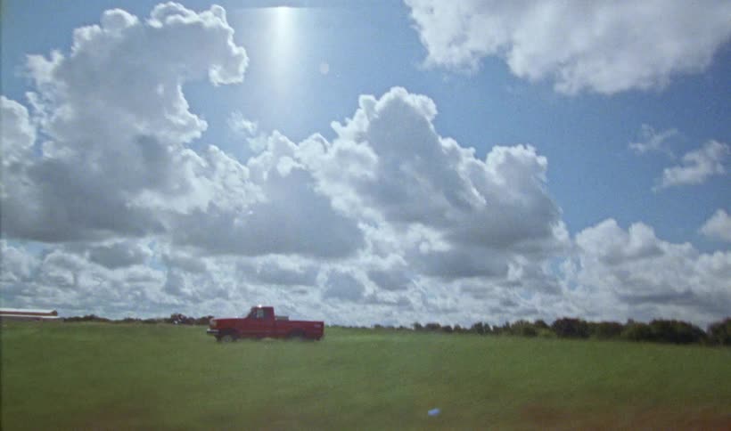 A truck is driving through a field of grass