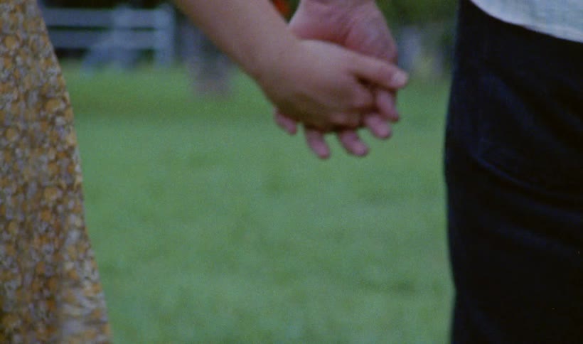 Close up of a woman holding the hand of a disabled person while walking on the park